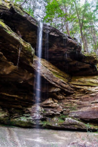 A waterfall over a big overhanging rock roof of layered sandstone in a long tall column, Sipsey River, Sipsey Wilderness, Alabama