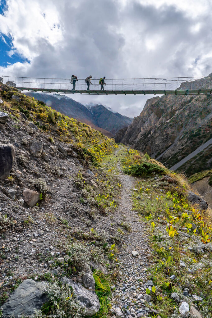 Three hikers crossing on a suspension bridge