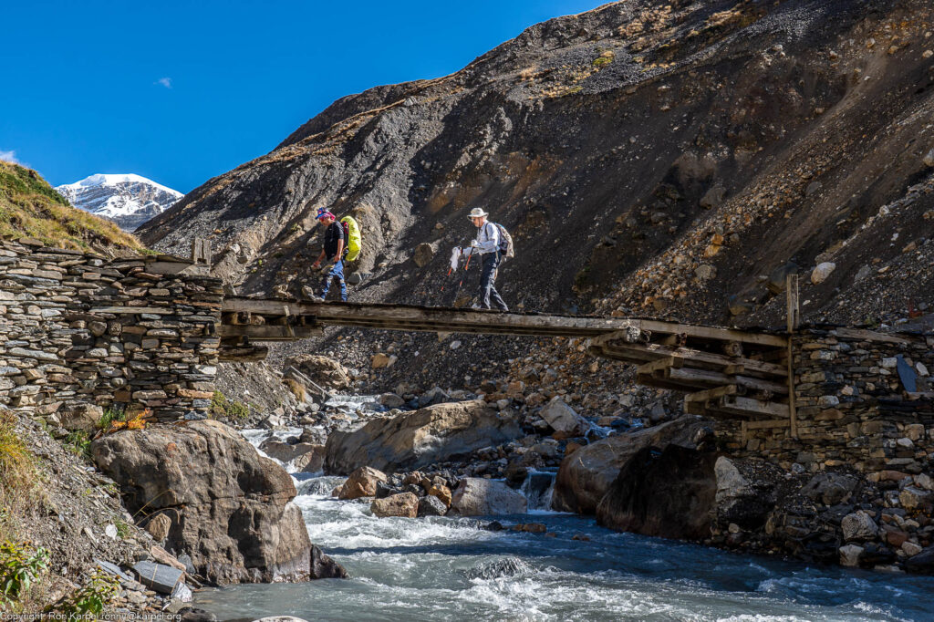 Hikers crossing a river on a wooden bridge